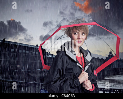 Woman walking under umbrella in rain Stock Photo