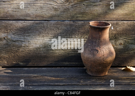 Cracked clay pot on a wooden rustic shelf Stock Photo