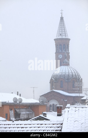 Vertical oriented image of church and roofs covered by first snow in Alba, Italy. Stock Photo