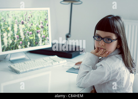 Girl sitting in front of desktop computer Stock Photo