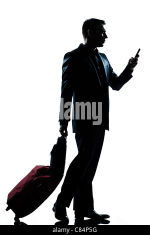 one  business traveler man walking with telephone and suitcase full length silhouette in studio isolated white background Stock Photo