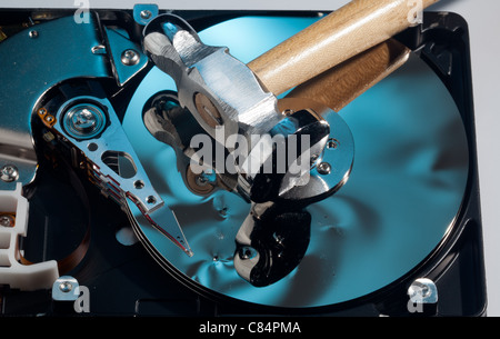 Magnetic disc inside a computer hd unit showing damage to the mirror surface of the magnetic discs and read write head from a hammer Stock Photo
