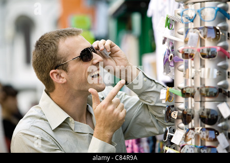Man trying on sunglasses in street market Stock Photo