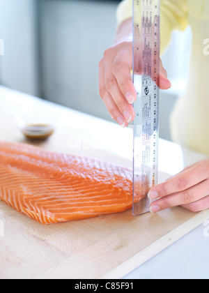 Woman Measuring Salmon to Determine Cooking Time Stock Photo