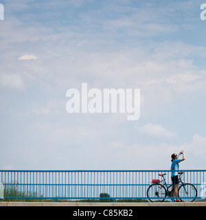 Female cyclist going over a bridge on a lovely sunny day (motion blurred image with copy space) Stock Photo