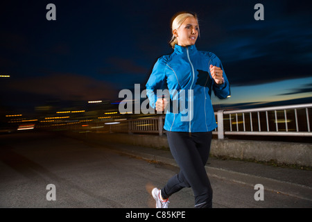 Woman Jogging at Dusk Stock Photo