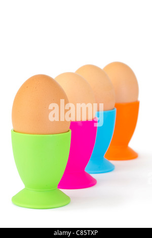 Colorful egg cups with boiled eggs in a row against a white background Stock Photo