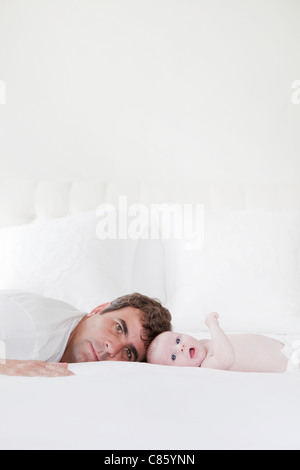 Dad and baby laying on bed Stock Photo