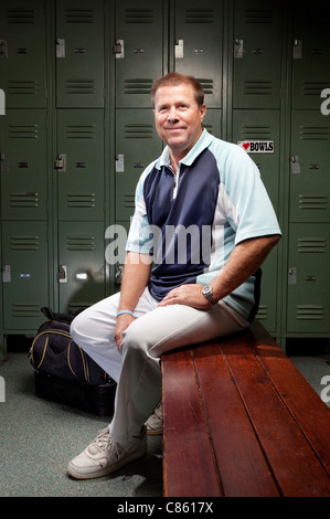 Caucasian man sitting on bench in locker room Stock Photo