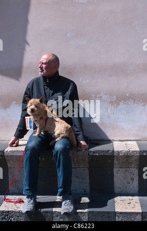 Middle aged tourist sitting on bench with his guide book and his dog in Orvieto, Umbria, Italy. Stock Photo