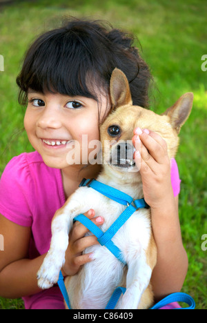 Hispanic girl holding and covering the eye of her chihuahua Stock Photo