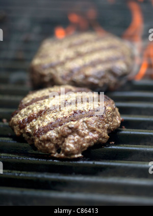 Hamburgers sizzling on the grill with flames Stock Photo