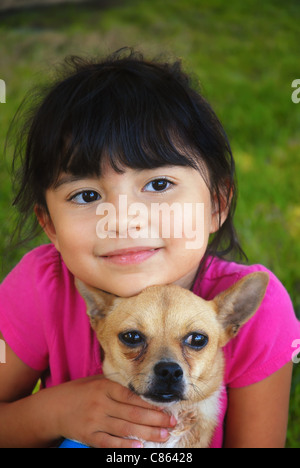 Little hispanic girl holding her chihuahua puppy Stock Photo