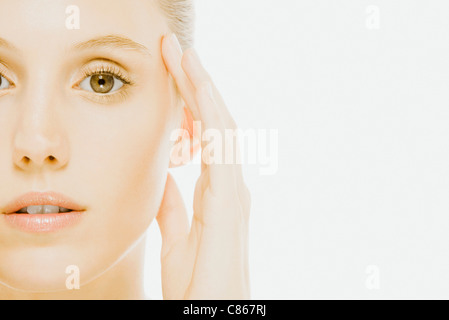 Young woman with hand held to side of head, close-up Stock Photo