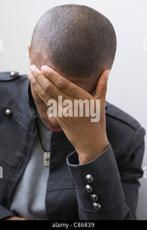 Young man covering face with hand Stock Photo