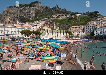The tiny beach at the popular resort town of Amalfi in southern Italy, packed with visitors in high summer Stock Photo