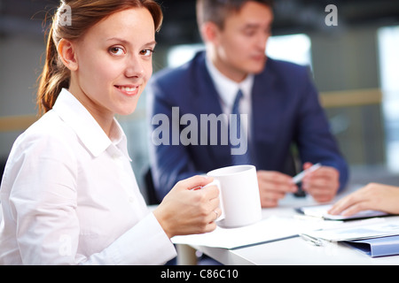 Portrait of smiling secretary drinking coffee during briefing Stock Photo