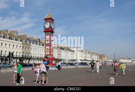 Holidaymakers on the promenade Weymouth Dorset England UK The clock tower erected to celebrate Queen Victoria's Golden Jubilee Stock Photo