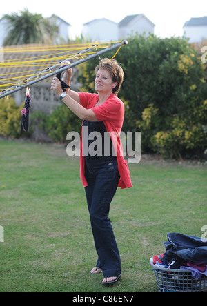 Middle aged woman hanging out washing on line in garden UK Stock Photo