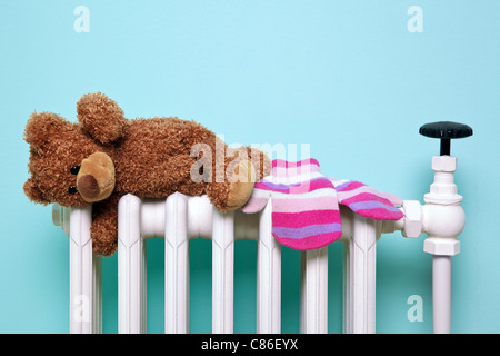 Childs teddy bear and gloves drying on a radiator Stock Photo