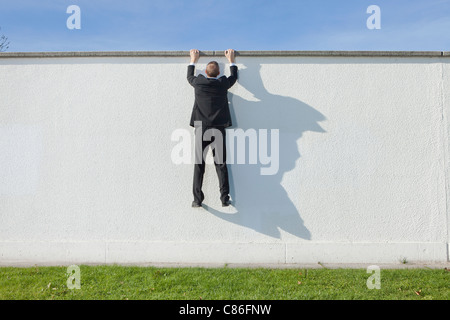 Businessman climbing over wall Stock Photo