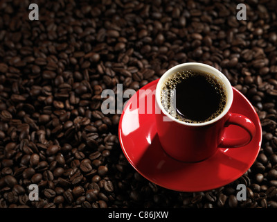 Red cup of coffee with a saucer on coffee bean background Stock Photo