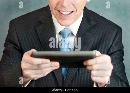 A close-up shot of a businessman looking at a tablet computer with excitement. Stock Photo