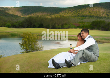Bride and Groom sitting at a lake while enjoying some champagne Stock Photo