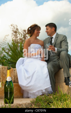 Bottle of champagne with Bride and Groom Newlyweds in the background Stock Photo