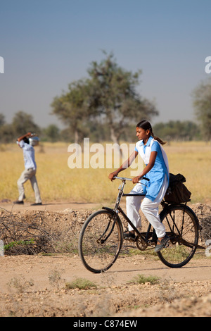 Young Indian girl in school uniform riding bicycle to her school near Rohet in Rajasthan, Northern India Stock Photo
