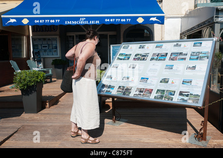 A woman looks at details of holiday villas for sale or rent outside an estate agents in Marseillan, southern France. Stock Photo