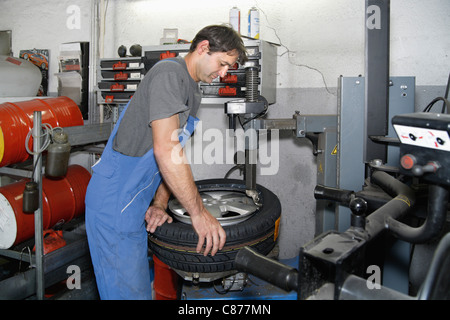 Germany, Ebenhausen, Mechatronic technician working on tyre in car garage Stock Photo