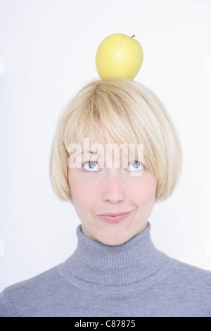 Close up of young woman balancing fruit on head against white background Stock Photo