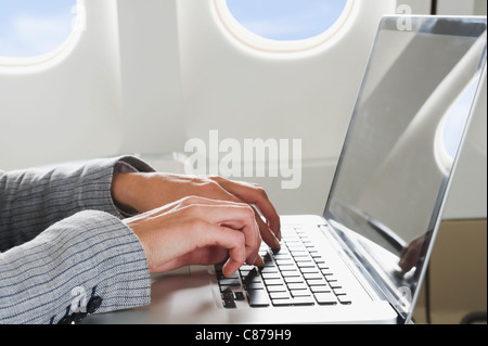 Germany, Bavaria, Munich, Close up of businesswoman's hand using laptop in business class airplane cabin