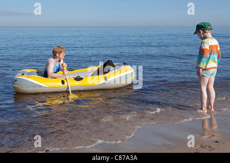 young boy watching his mother and the family dog in a rubber boat Stock Photo