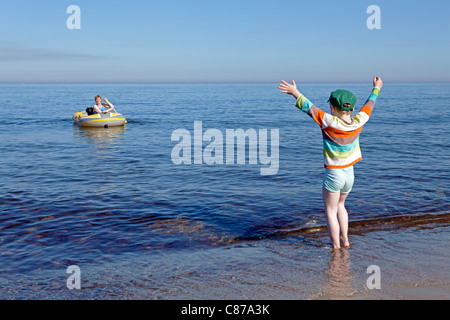 young boy watching his mother and the family dog in a rubber boat Stock Photo