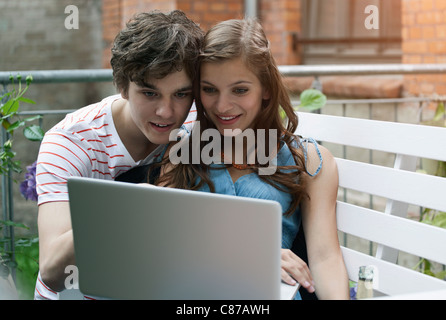 Germany, Berlin, Close up of young man and woman using laptop, smiling Stock Photo