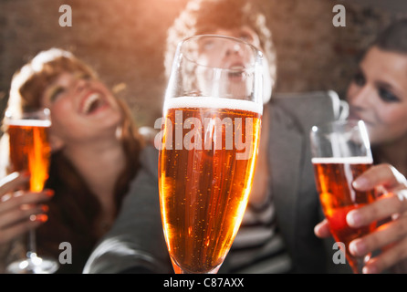Germany, Berlin, Close up of champagne glass in front of friends having party, smiling Stock Photo
