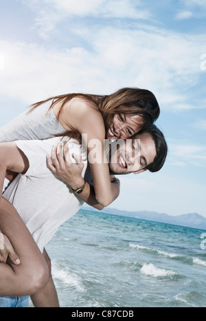 Spain, Majorca, Young man carrying woman on back at beach Stock Photo