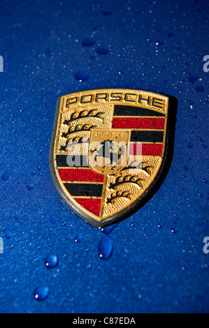 close up of Porsche badge on blue car in the wet Stock Photo