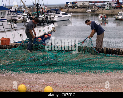 Horizontal portrait of Fishermen mending nets in the harbour, Normandie France Stock Photo