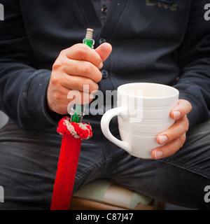 Close up of an unidentifiable man smoking a shisha pipe and holding a mug of tea Stock Photo