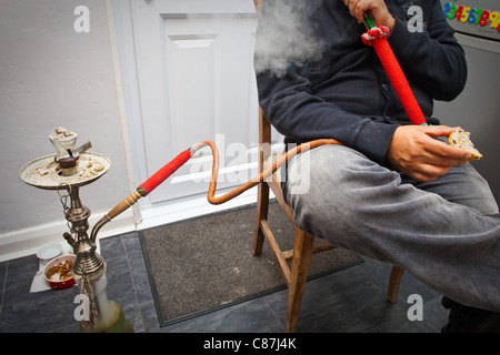 An unidentifiable man smoking a shisha pipe Stock Photo