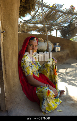 Indian Hindu woman at home made of mud bricks coated with cow dung in Bishnoi village near Rohet in Rajasthan, Northern India Stock Photo