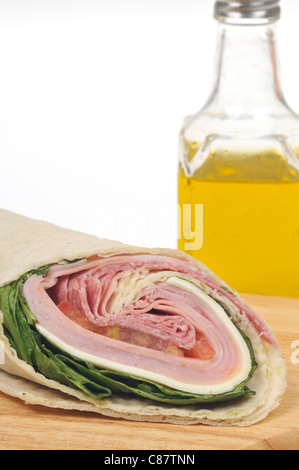 Italian deli meat wrap sandwich with lettuce, cheese & tomato and bottle of olive oil on white background. USA Stock Photo