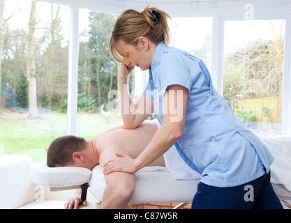 female massage therapist treating male patient Stock Photo