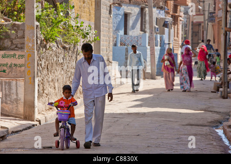 Indian man with child on tricycle in the village of Narlai in Rajasthan, Northern India Stock Photo