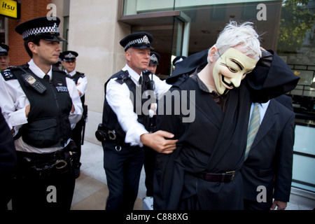 Julian Assange of WikiLeaks at the Occupy London demonstration 15th October 2011. Seen here, he tries to get through police lines wearing a black cape, hood and mask. He was immediately asked to take off the mask where upon he was dragged through, questioned and released. Stock Photo