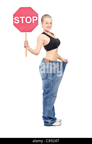 Full length portrait of a weightloss girl holding a traffic sign stop Stock Photo