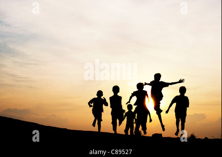 Silhouette of young Indian boys running and jumping against at sunset in India